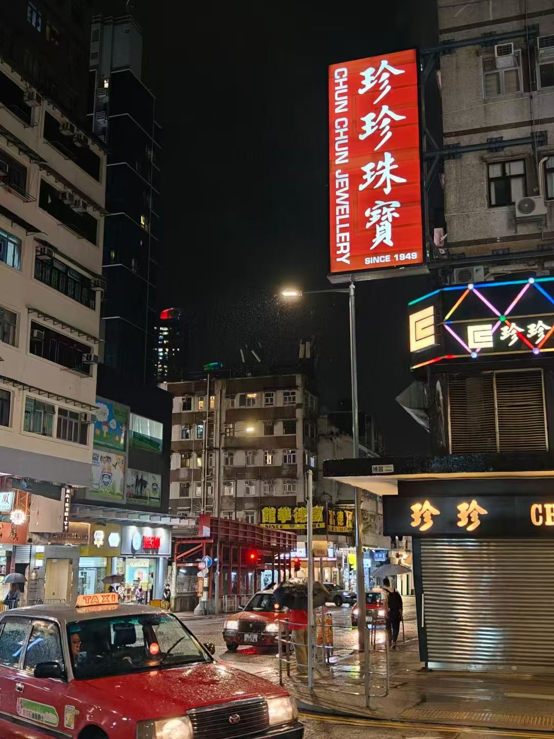 香港九龙城福佬村道雨夜的红色出租车、霓虹招牌与路面倒影